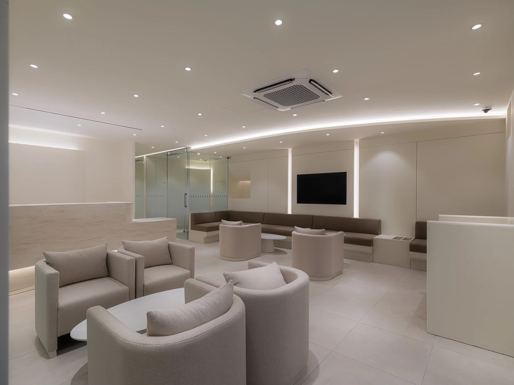 The main lounge of LEE HAKSOO Plastic Surgery with soft lighting, armchairs, and a travertine reception counter