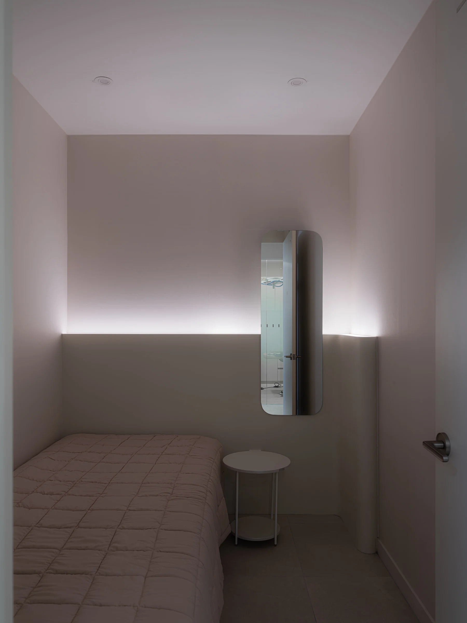 A private recovery room with a bed, soft indirect lighting, and a mirror