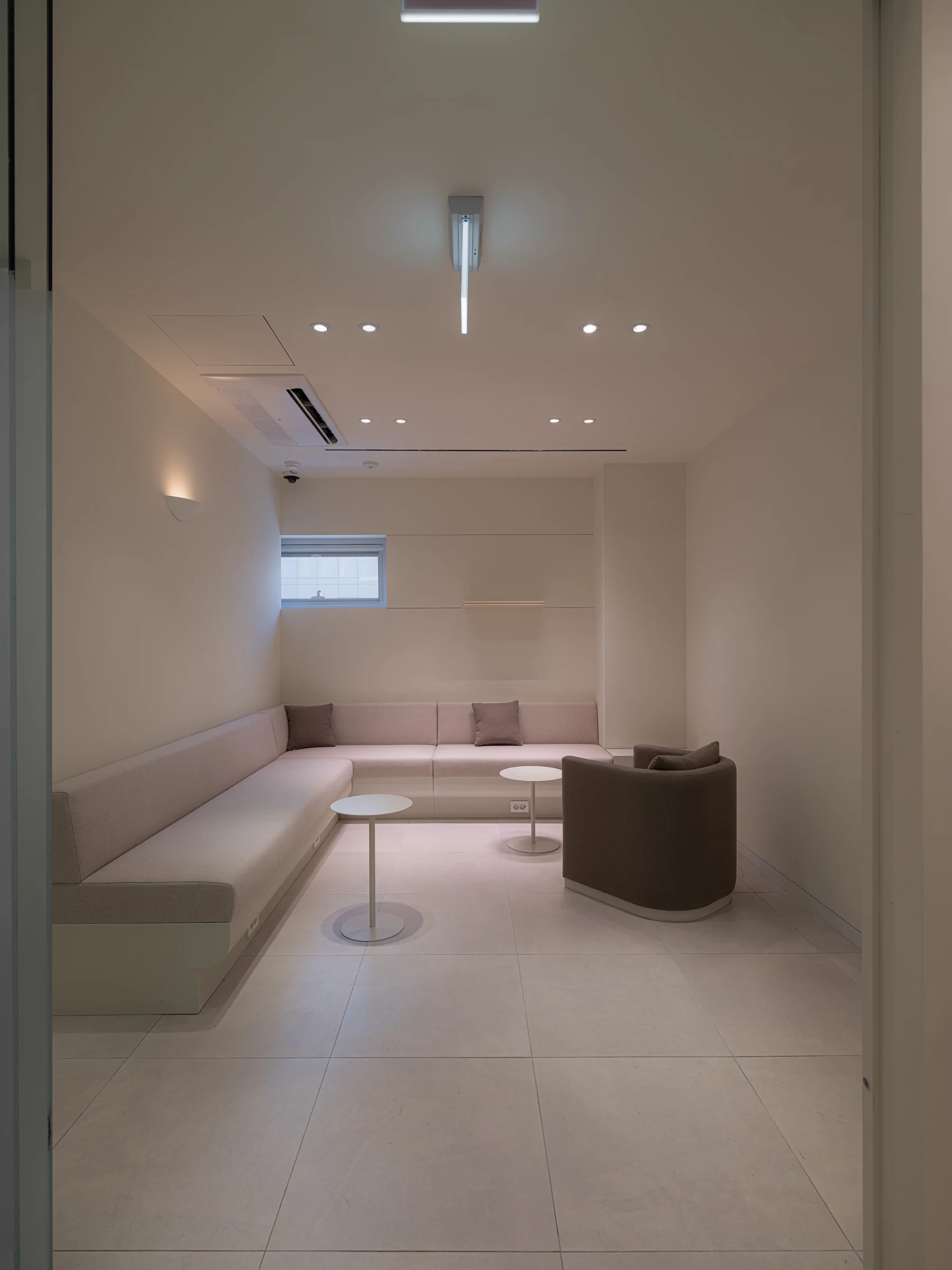 A private rest lounge with a long bench sofa, an armchair, and soft lighting